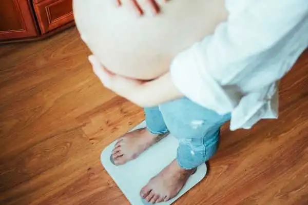 Image of woman weighing herself and experiencing weight gain through pregnancy Poulton
